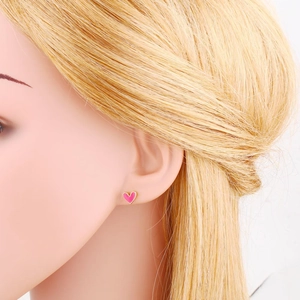 Close-up of heart stud earrings with pink enamel and gold trim on an ear model