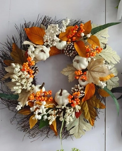 Detail of autumn wreath with white pumpkins, maple leaves, pine cones and berries