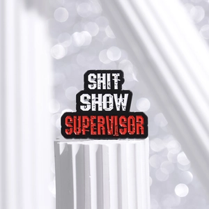 Funny Shit Show Supervisor enamel pin badge on a white column for clothing accessories