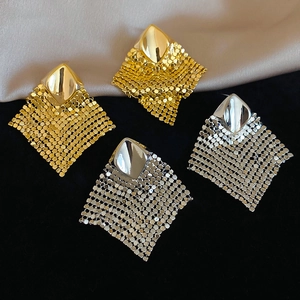 Detail of square metal mesh earrings in gold and silver finish on champagne silk fabric