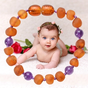 Baltic amber and amethyst baby teething bracelet on warm white plush background