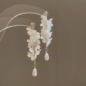 Detailed macro view of white flower tassels and a pearl drop on golden earrings