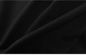 Close-up of black sports trousers showing premium knitted fabric texture and weave detail