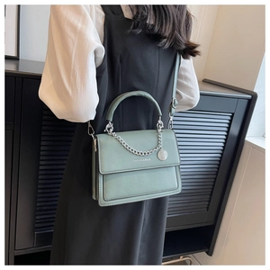 Detail of dark green PU leather crossbody bag with silver chain and fashion lettering