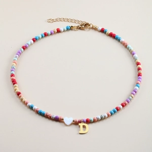 Detail of colorful beaded necklace with golden letter D pendant and white heart charm