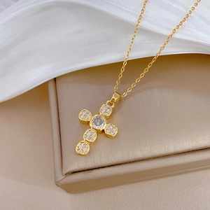 Detailed close-up of a gold cross pendant necklace with sparkling micro-pave zircons