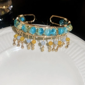 Détail d'un bracelet manchette doré avec des perles en cristal bleu et pendentifs à franges
