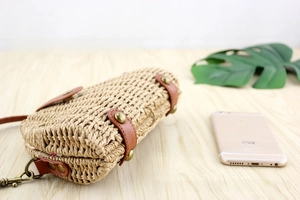 Detail view of woven straw crossbody bag with brown leather strap and floral lining