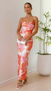 Détail de robe maxi fleurie montrant l'imprimé rose orange et la fente sur tissu satiné