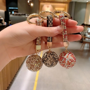 Sparkly crystal ball car keychain with diamond bow charm in gold, black and red colors