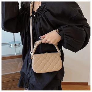 Detail of beige quilted bag with pleated handle and gold hardware on model