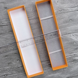 Orange rectangular watch gift box with velvet interior and elastic band shown on wood