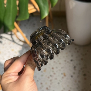 Detail of smoky gray translucent pumpkin hair claw clip held by hand in home setting