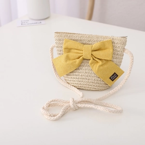 Detail of child straw bag with yellow bow and hand made label on white surface