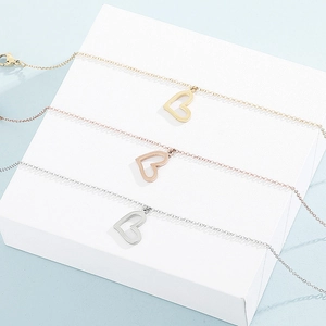 Three minimalist hollow heart necklaces in gold, rose gold and silver on geometric blocks