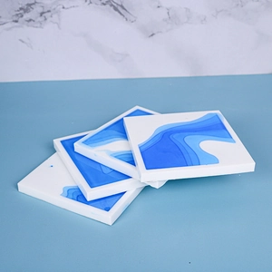 Set of four square resin coasters with ocean blue wave texture on marble background