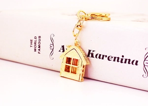Close-up of golden house-shaped keychain with rhinestones and metal lobster clasp on a book