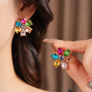 Close-up of vintage floral earrings with colorful gemstones and elegant gold-plated setting