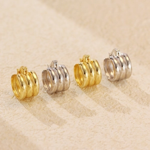 Macro shot of minimalist silver and gold triple-layered hoop earrings on a stone surface