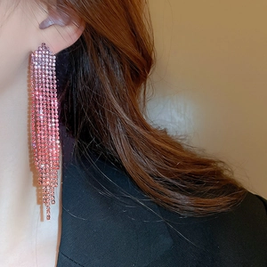 Close-up of pink rhinestone long fringe earrings worn with elegant black attire