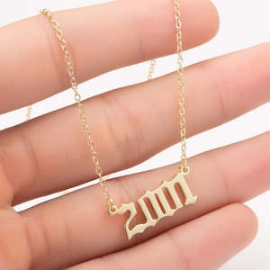 Detailed close-up of a golden 2001 year pendant in gothic font on a delicate chain necklace