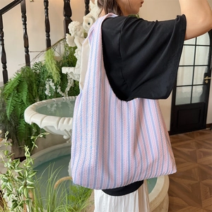 Detailed texture of pink and purple striped canvas tote bag worn on shoulder