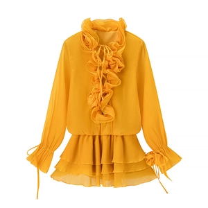 Detail of yellow ruffled top featuring a 3D flower neckline and delicate tiered layers