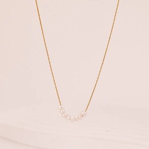 Elegant 18k gold-plated choker with eight white freshwater pearls on a soft pink background