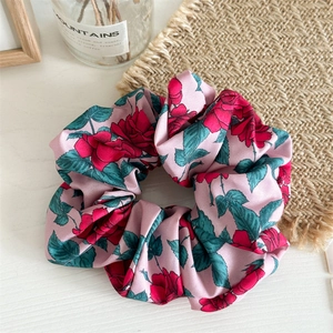 Detail of pink fabric scrunchie with red rose floral print and soft texture