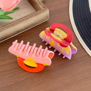 Chic acetate hair claws in pink and purple floral patterns on a dark wooden surface