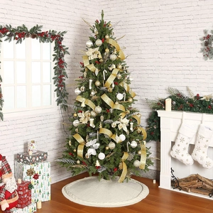 Close-up of a white knitted Christmas tree skirt with festive ornaments and golden decor
