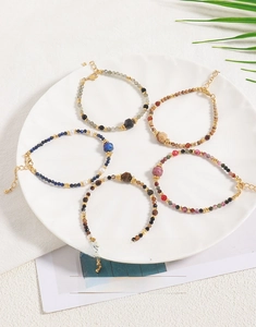 Detail of five handmade natural stone beaded bracelets with adjustable gold lobster clasps