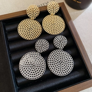 Detail of woven mesh texture on gold and silver hollow circular drop earrings