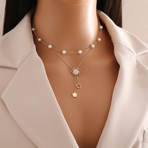Elegant double layer gold necklace with white pearls and floral pendants on a model