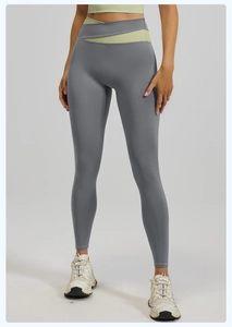 Detalle de leggings de yoga de cintura alta con tela gris oscuro y cintura cruzada verde
