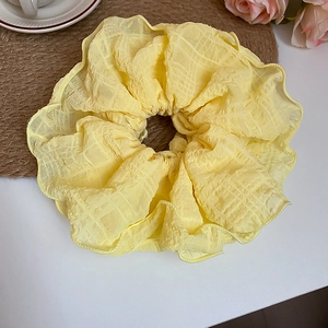 Detail of yellow checkered organza scrunchie with soft ruffles on a bright desk