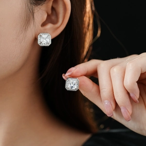 Vue macro de boucles d'oreilles carrées en argent et zircone portées avec serti halo