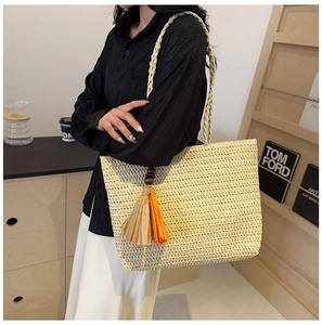 Detail of woven straw tote bag with decorative colorful tassel and large capacity design