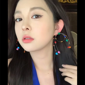 Gros plan d'un mannequin portant de grandes boucles d'oreilles créoles avec perles colorées