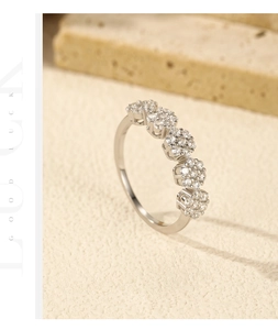 Macro shot of silver S925 floral cluster ring on textured stone with warm lighting
