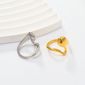 Polished gold and silver rings with an abstract fluid shape on a white pedestal
