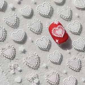 Détail macro de stickers ongles blancs 3D avec motifs de cœurs et nœuds tricotés