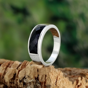 Silver stainless steel ring with rectangular blue sandstone on a natural wood base