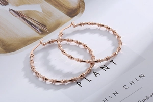Detailed view of rose gold bamboo style hoop earrings with a polished metallic texture