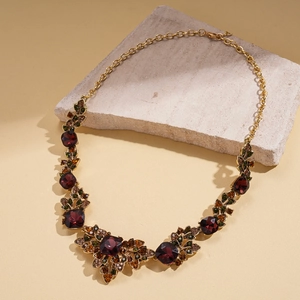 Detail of vintage palace style leaf necklace with dark red gemstone and gold chain
