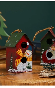 Détail de maisons de Noël en métal rouge et vert avec motifs bonhomme de neige sur table bois