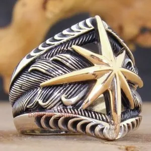 Macro detail of vintage silver men's ring with gold star pattern and feather texture