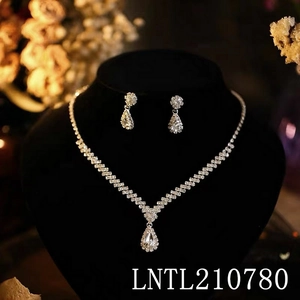 Detail shot of a silver V-shaped rhinestone necklace and teardrop earrings on black velvet