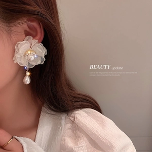 Detailed view of floral lace earrings with pearl drop on a model in soft lighting