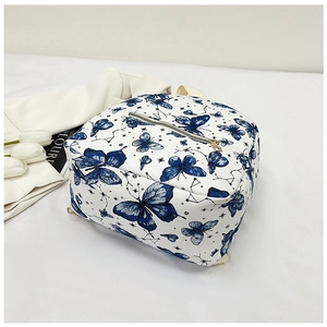 Detail of blue butterfly pattern on white PU leather backpack with gold zippers